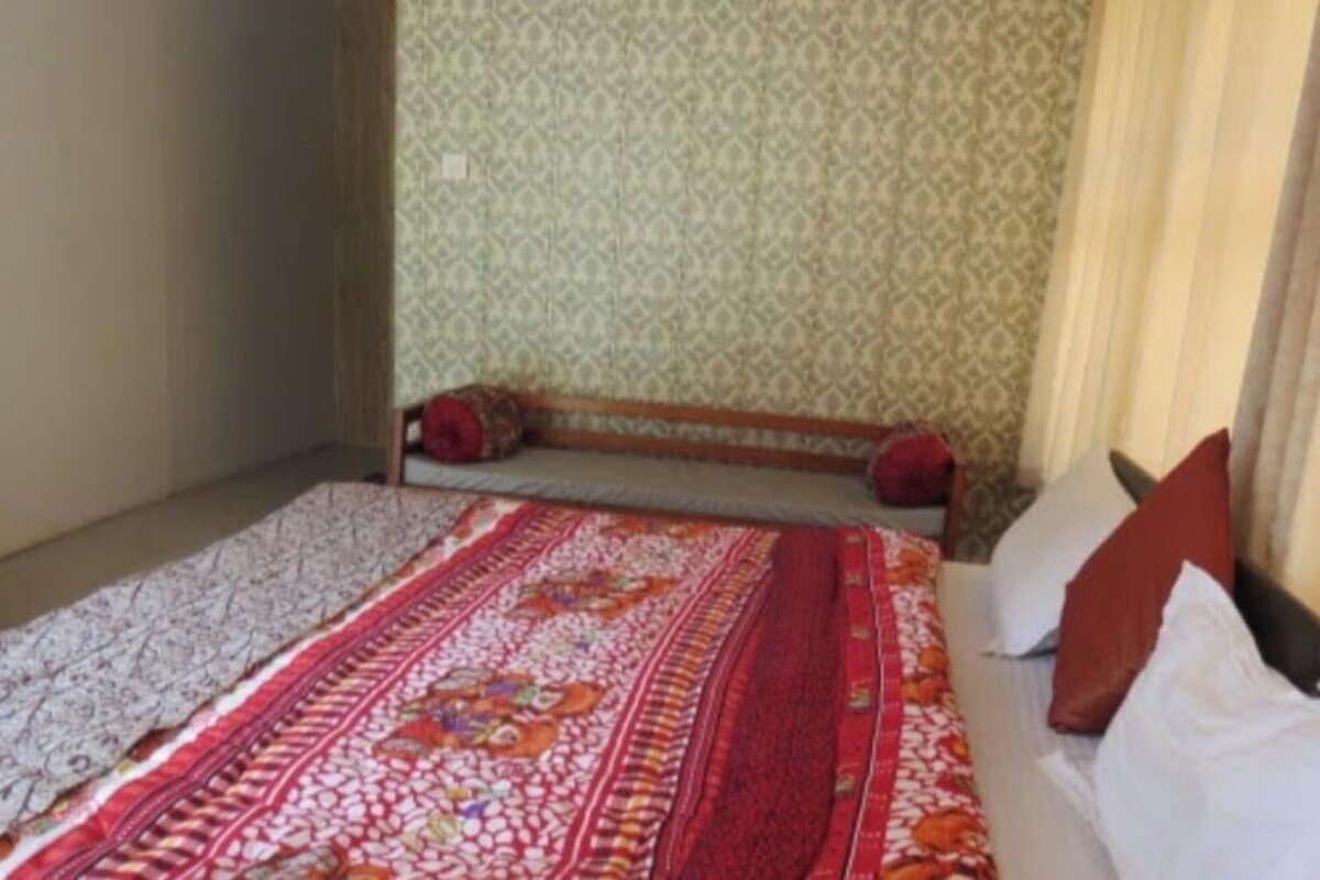A room with a bed, a patterned wall, and a curtain.