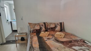 A bedroom with a bed, two pillows, a nightstand, and a door. - Apartment 'Rehkitz' with Mountain View (Bad Lauterberg im Harz)