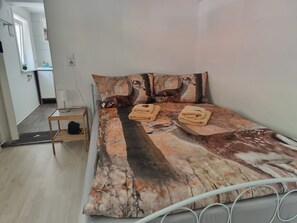 Ein Schlafzimmer mit einem Bett, zwei Kissen, einem Nachttisch und einer Tür.