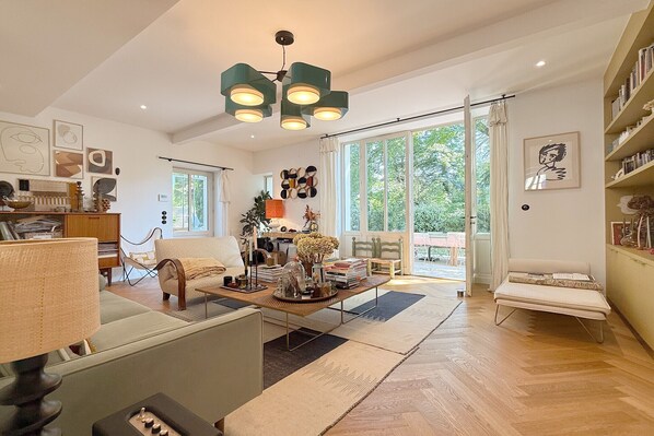 Ein geräumiges Wohnzimmer mit Klavier, Sofa, Couchtisch und Bücherregal.