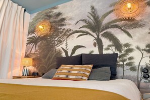 Ein Schlafzimmer mit Bett, Kissen, Nachttisch, Lampe und Wandbild.