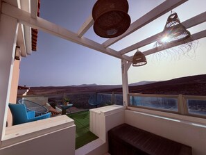 A balcony with a view of the landscape, a seating area with a bench, and a table with chairs. - Caleta de Fuste 3-Bed Villa on Golf Course - Padel, Beaches, Bars & Restaurants (Castillo Caleta de Fuste)