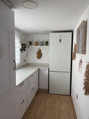 Een kleine keuken met witte kasten, een inbouwkoelkast en een klein aanrecht.