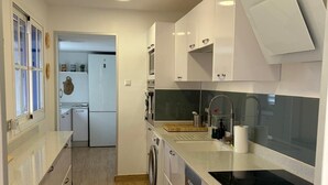 Een moderne keuken met witte kasten, een inbouwoven, een vaatwasser en een zwart inductiekookplaat.