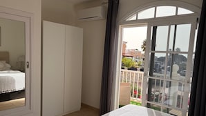 Een slaapkamer met een bed, kledingkast en een balkon met uitzicht.