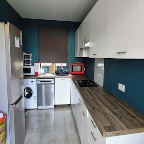 Uma cozinha compacta com máquina de lavar, micro-ondas e fogão.