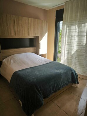 Ein Schlafzimmer mit einem Bett, einem Holzkopfende und einem Fenster mit Vorhängen.