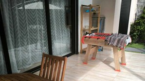 Une terrasse avec une table et des chaises en bois, un baby-foot et une bibliothèque.