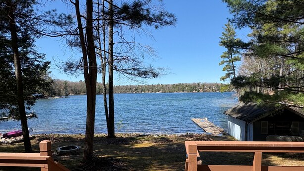Une terrasse au bord du lac, avec des bancs en bois, un petit abri et une jetée qui s’avance dans l’eau.