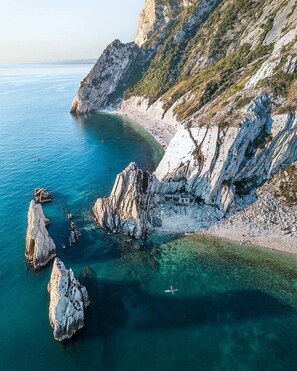 Eine Küstenlandschaft mit felsigen Klippen, klarem blauen Wasser und einem Sandstrand.