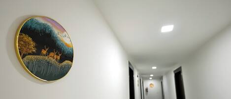 A hallway with a round, framed artwork on the left wall and a door at the end.