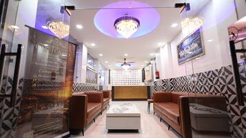 A hotel lobby with leather sofas, a chandelier, and a reception desk.