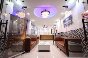 A hotel lobby with leather sofas, a chandelier, and a reception desk. - Hotel Finch Grand by Revaantra   (Haridwar)