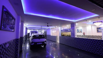 A hallway with a white SUV parked, a ceiling fan, and a chandelier.