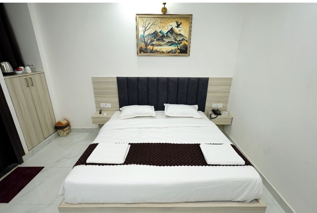 Un dormitorio ordenado con cama, mesitas de noche, un armario y un cuadro colgado en la pared.