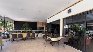 An outdoor dining area with tables and chairs, a blackboard, and a view of the street. - Cemsa Sunparadise BOUTİQUE HOTEL (Alanya)