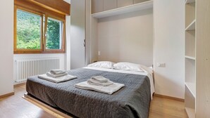 Ein Schlafzimmer mit einem Bett, zwei Fenstern, einer Heizung und Holzboden.