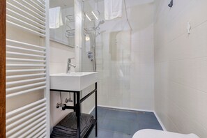 A bathroom with a white sink, a glass shower enclosure, and a towel rack.