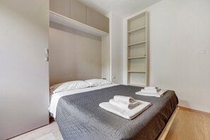 A bedroom with a bed, a wardrobe, and a built-in shelving unit.