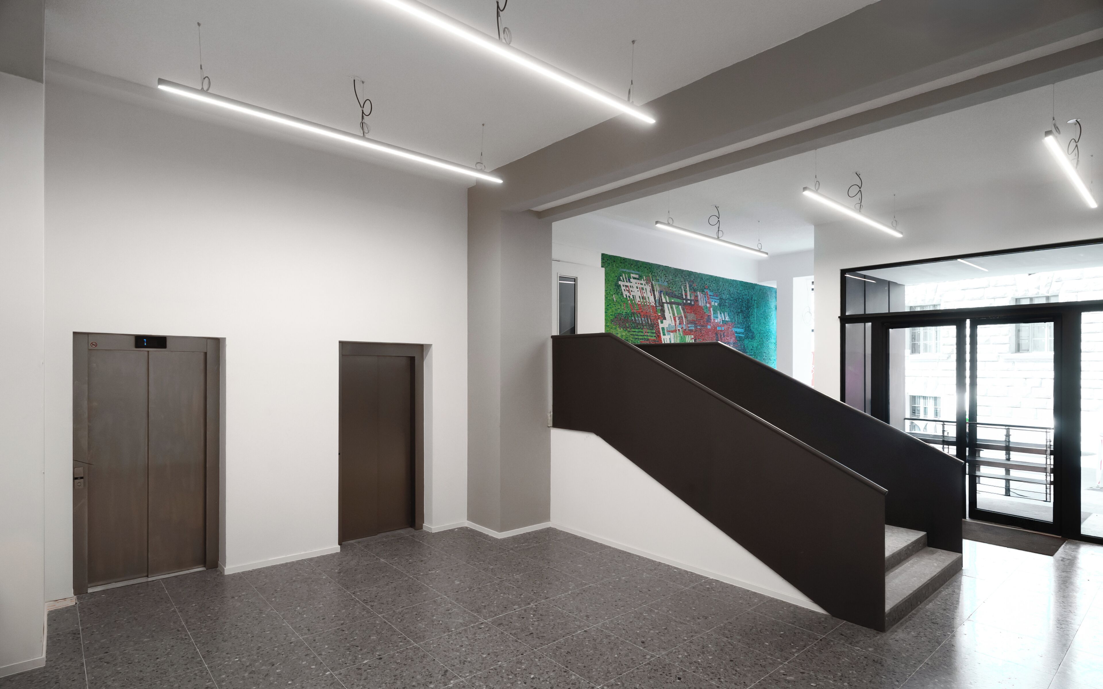 A modern interior with a staircase, two elevator doors, and a colorful mural.