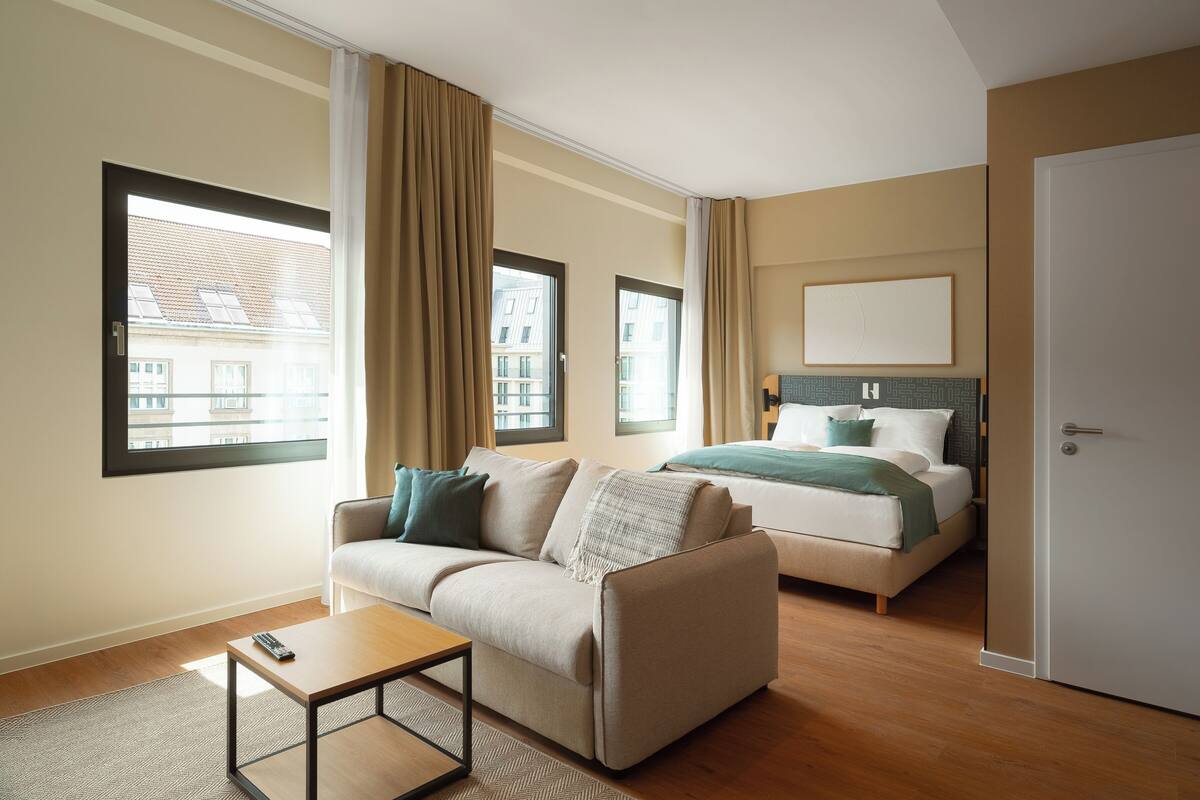 Una habitación de hotel con sofá, cama, una mesita y una puerta.