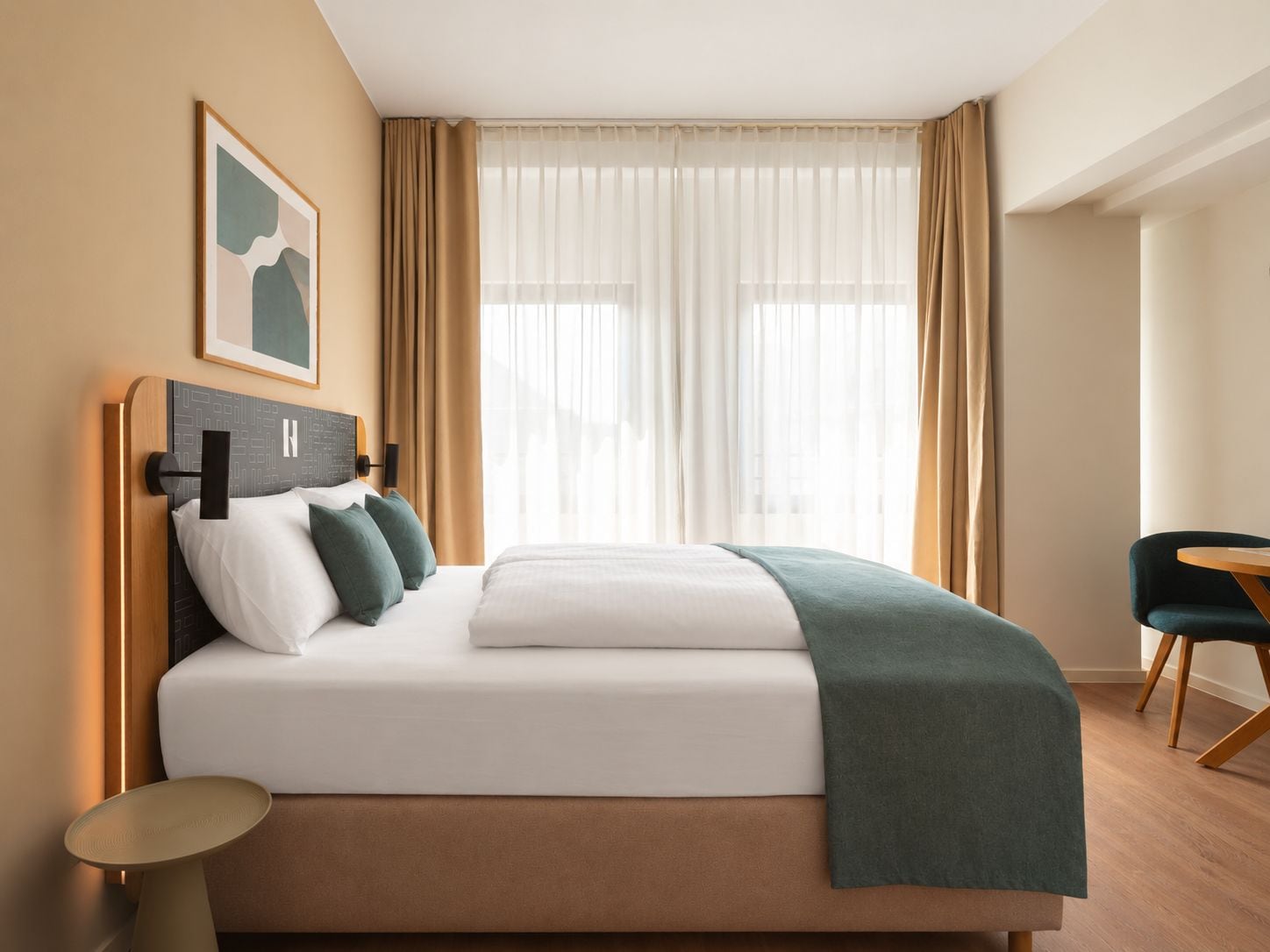 Una habitación de hotel con cama, mesita de noche, una silla y una ventana con cortinas.