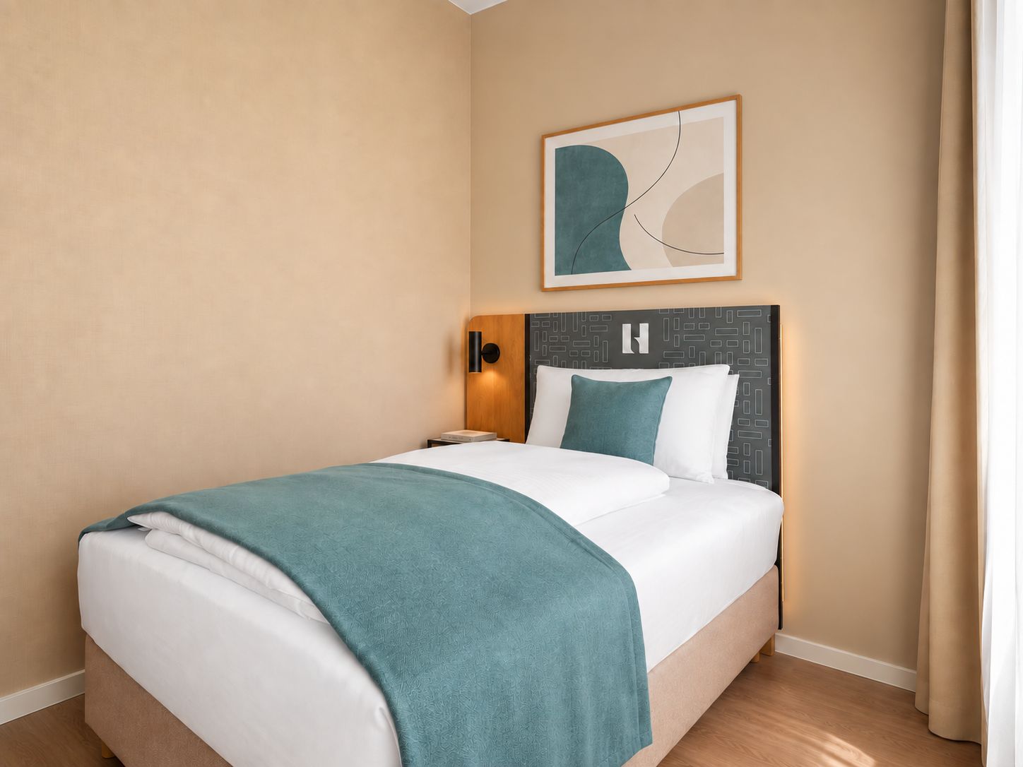 Habitación de hotel con cama, mesita de noche, lámpara de pared y una obra de arte abstracta enmarcada.