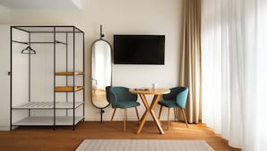 Een kamer met een garderobe, een televisie, twee stoelen, een tafel en een spiegel.