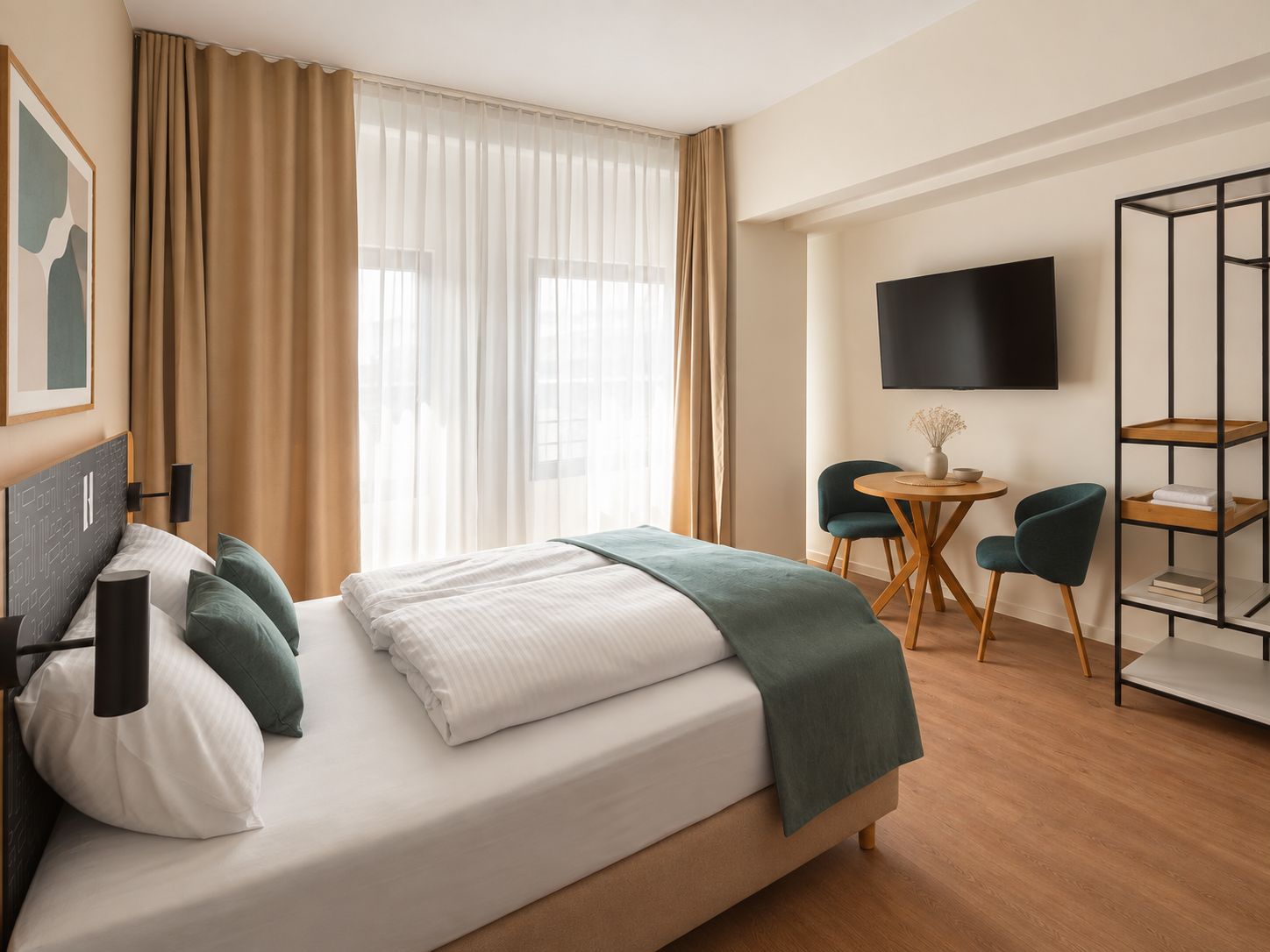 A hotel room with a bed, a desk, two chairs, a TV, and a bookshelf.