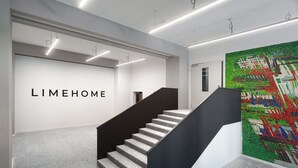 Een modern interieur met een trap, een muur met de tekst 'LIMEHOME' en een kleurrijke mozaïekwand.