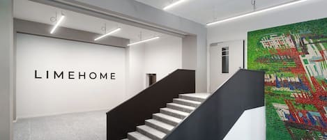 Een modern interieur met een trap, een muur met de tekst 'LIMEHOME' en een kleurrijke mozaïekwand.