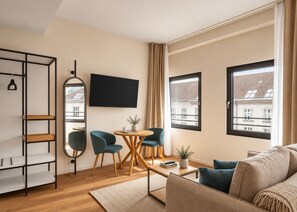 A modern living room with a sofa, two chairs, a coffee table, a TV, and a bookshelf. - Limehome Berlin Klosterstraße (Berlin)