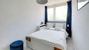 A bedroom with a bed, bedside table, lamp, and a window with curtains. - RentPlanet - Apartament Zielińskiego (Wrocław)