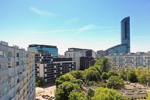 Un paysage urbain avec des bâtiments modernes, un gratte-ciel incurvé imposant et un espace vert arboré.