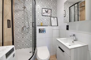 Une salle de bain moderne équipée d’une douche, de toilettes, d’un lavabo et d’un mur décoré d’un motif.