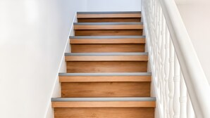 A wooden staircase with white balustrades, leading upwards. - Apartment 'Hirschkönig' with Mountain View (Bad Lauterberg im Harz)