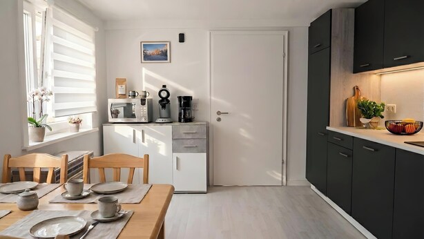 A compact kitchen with a dining area, featuring a microwave, coffee maker, and a small refrigerator. - Apartment 'Hirschkönig' with Mountain View (Bad Lauterberg im Harz)