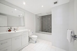 Et moderne badeværelse med hvid vask, toilet og bruseområde.