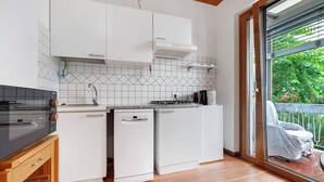 A compact kitchen with white cabinets, a built-in oven, and a dishwasher. - Apartment 'Bilocale Ulrica' with Private Terrace and Wi-Fi (Nago–Torbole)