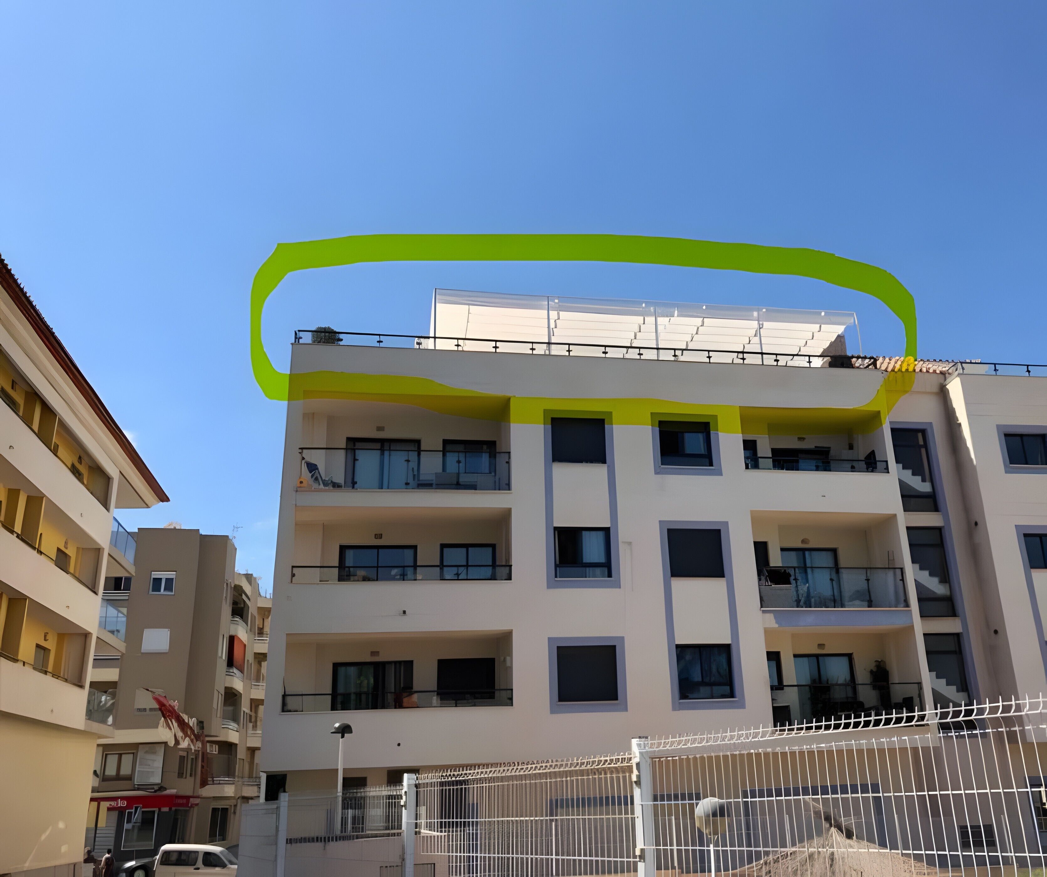 Un immeuble à plusieurs étages doté de balcons, d’une clôture blanche et surplombant un ciel dégagé.