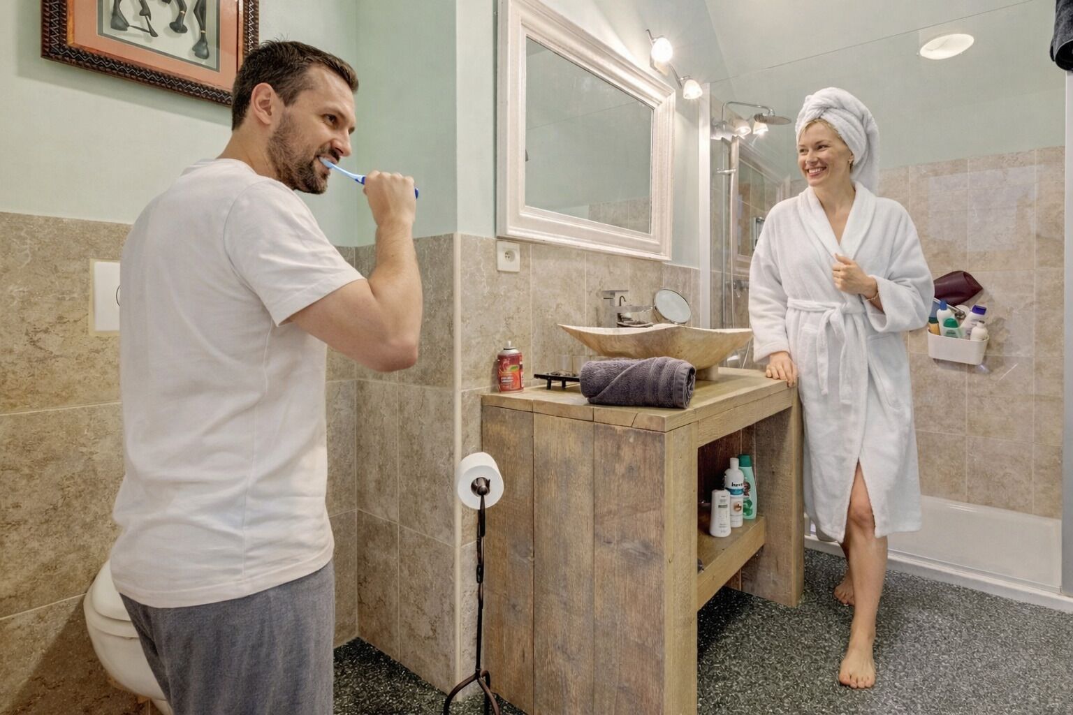 A bathroom with a wooden vanity, a large mirror, and a sink.