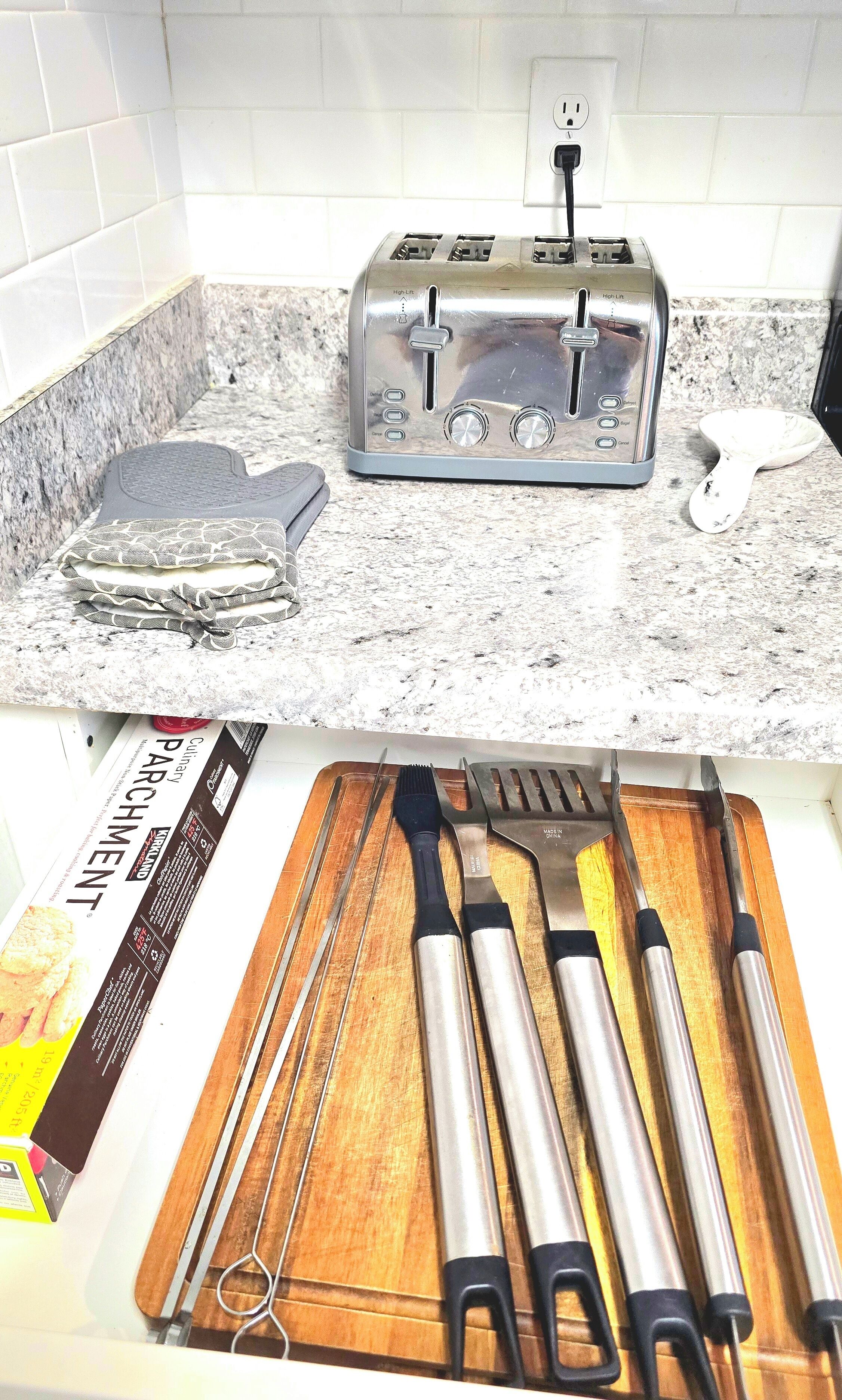 Una cocina con un tostador, una tabla de cortar con utensilios y una revista.