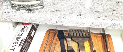 Una cocina con un tostador, una tabla de cortar con utensilios y una revista.