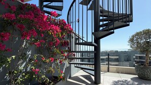 A spiral staircase with a metal railing, a potted plant, and a flower box with pink flowers. - Luxury Penthouse with the view (Estepona)