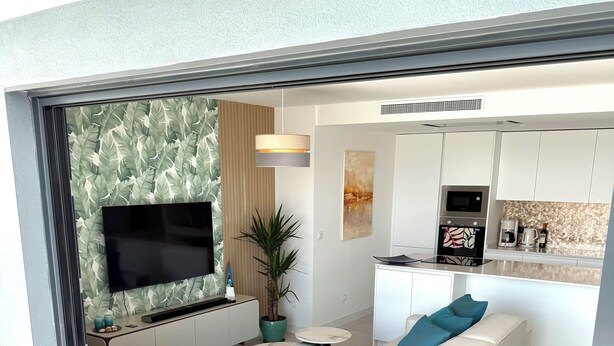 A modern living room with a sectional sofa, a flat-screen TV, a coffee machine, and a kitchen area. - Luxury Penthouse with the view (Estepona)