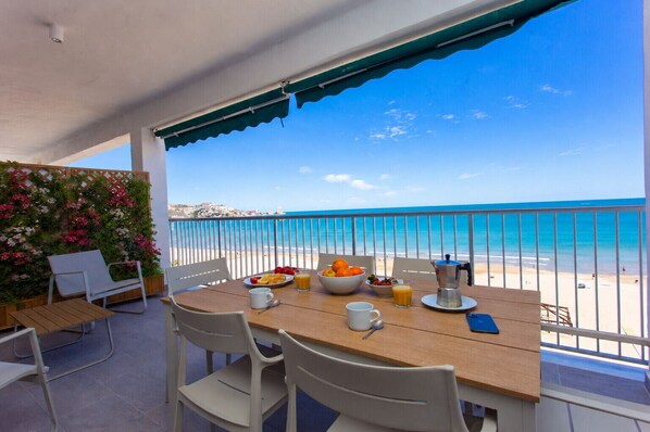 Ein Balkon mit Frühstückstisch, der Blick auf einen Strand gewährt.