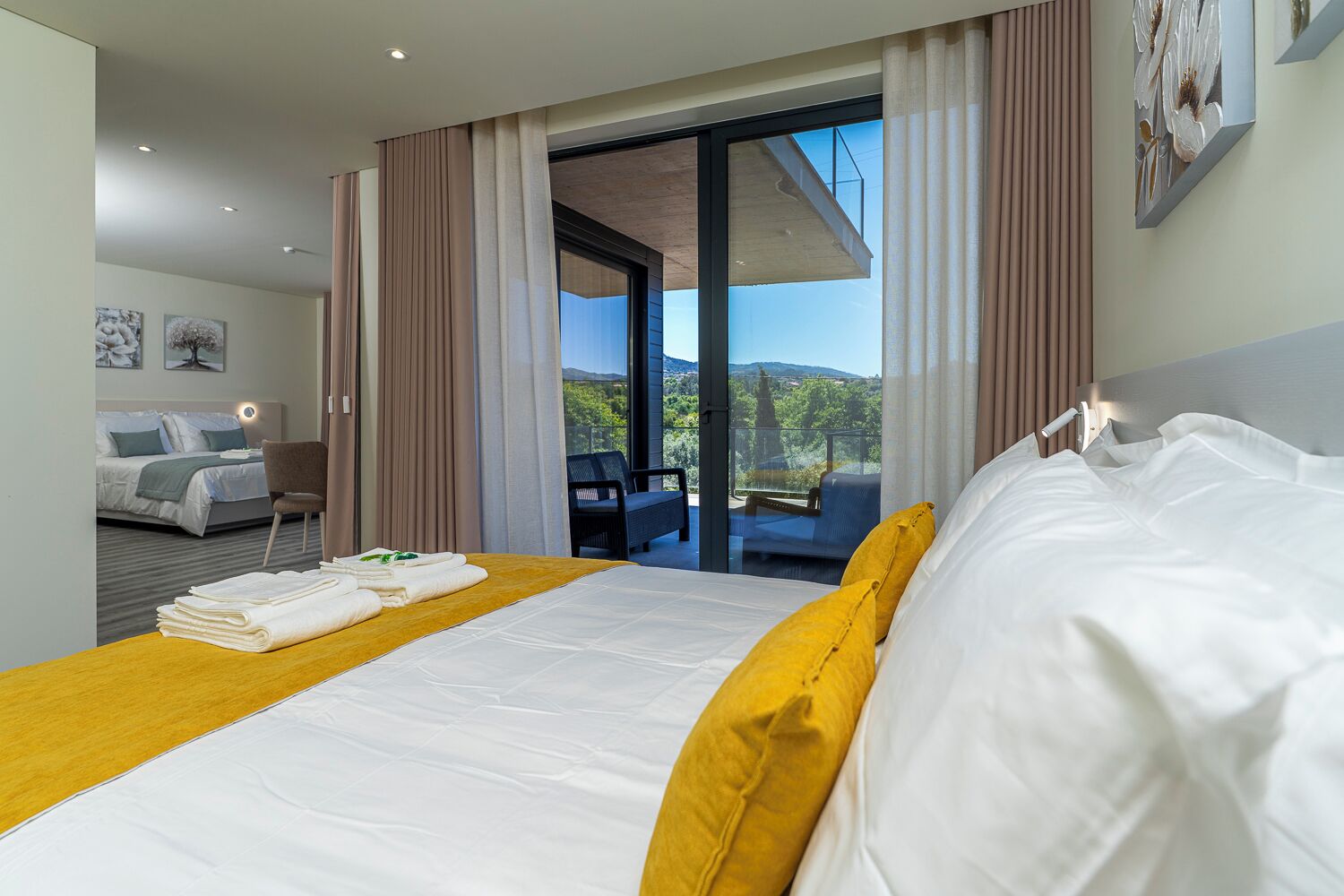 Una camera d'albergo con un letto, vista sull'esterno e un balcone.