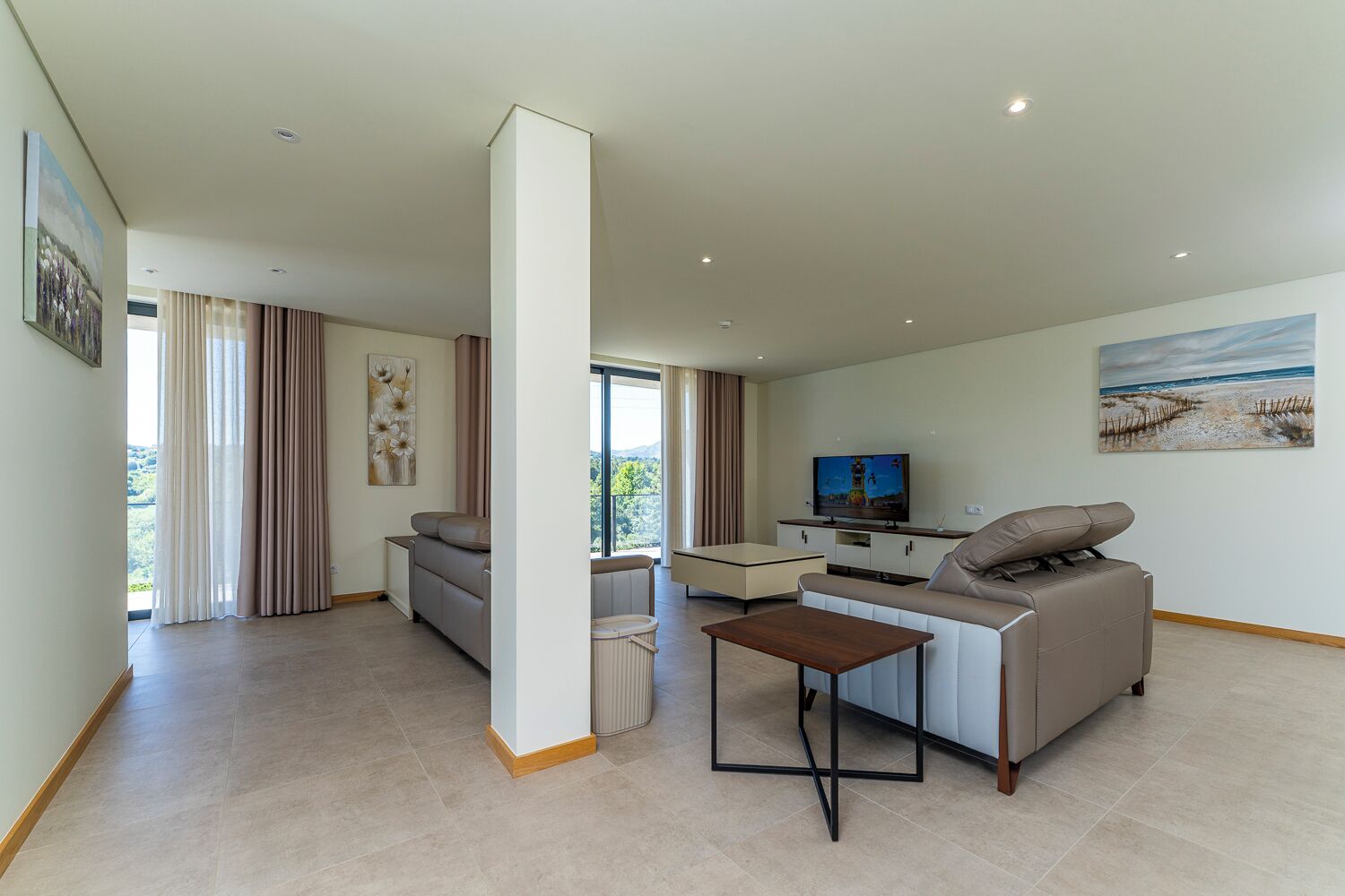 A modern living room with a sofa, a coffee table, a TV, and a painting on the wall.