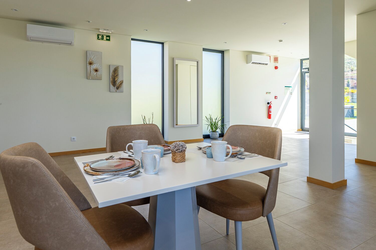 Un coin repas avec une table blanche, des chaises marron et une plante en pot.
