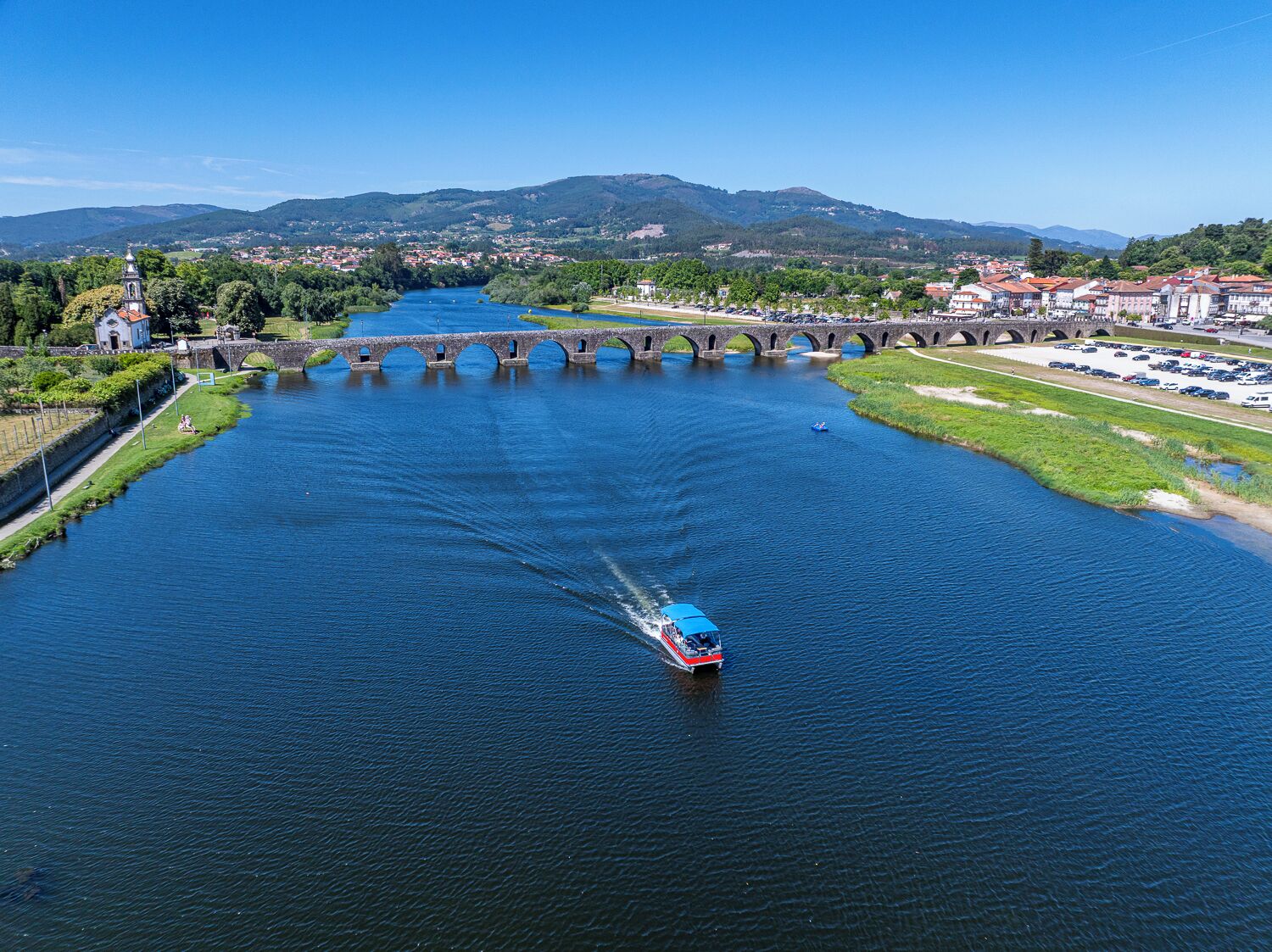 A river with a bridge, a boat, and a town in the background.